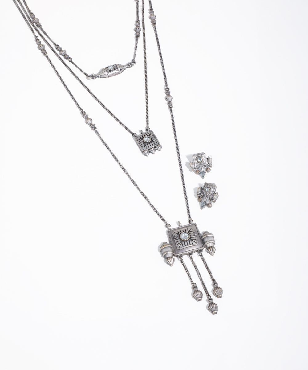 Silver necklace with pendant and matching earrings on a white background