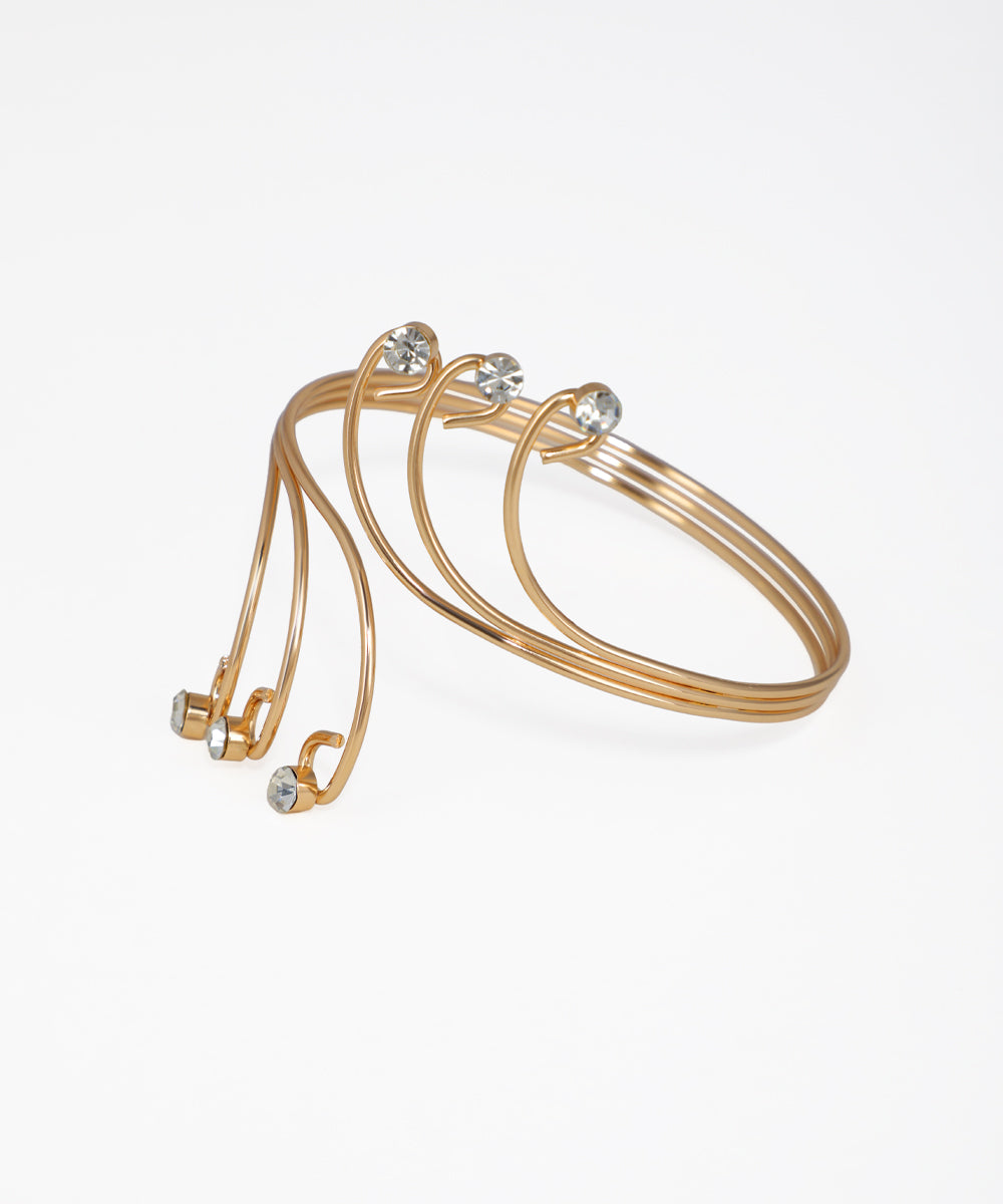 Set of gold bangles with small crystals on a white background