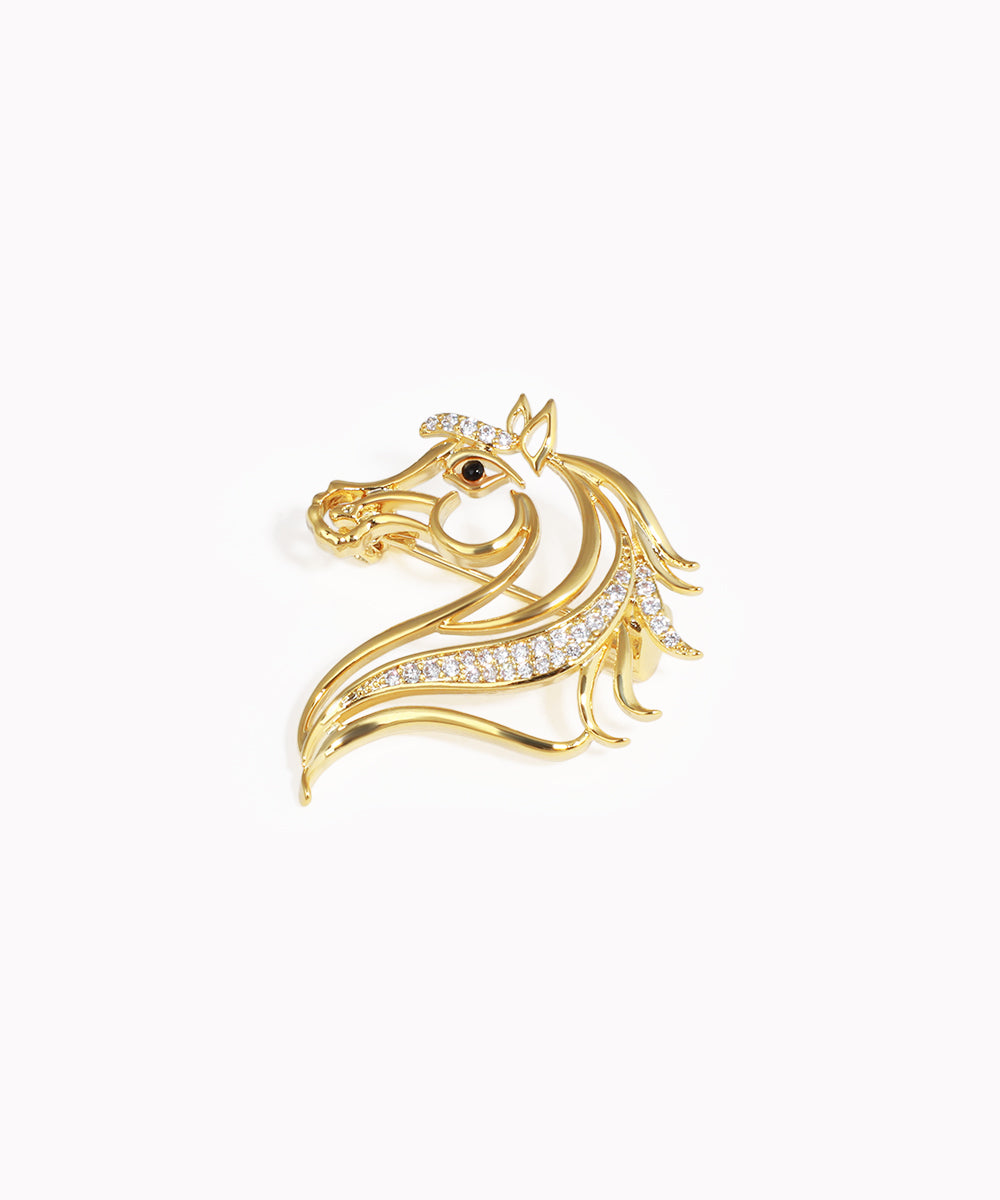 Gold-tone brooch with a stylized horse head design, featuring clear stones and a single dark eye stone