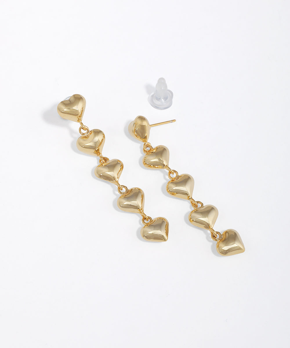 Gold-tone drop earrings with cascading puffed heart links and a shiny finish