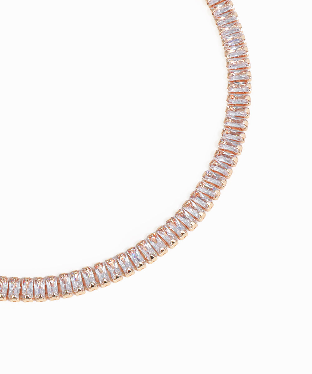 Rose gold necklace with clear gemstones on a white background