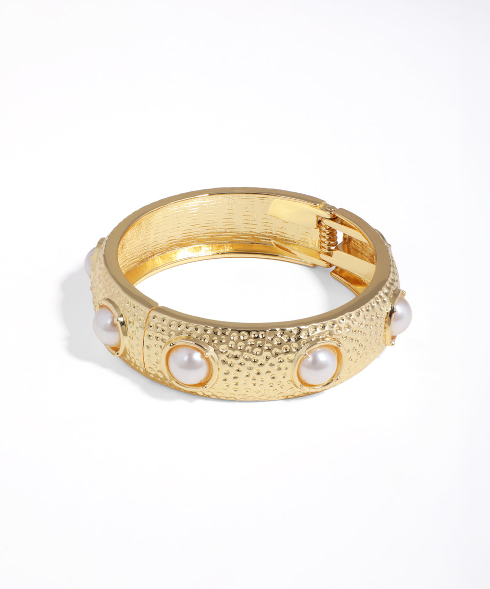 Gold ring with pearl-like stones on a white background