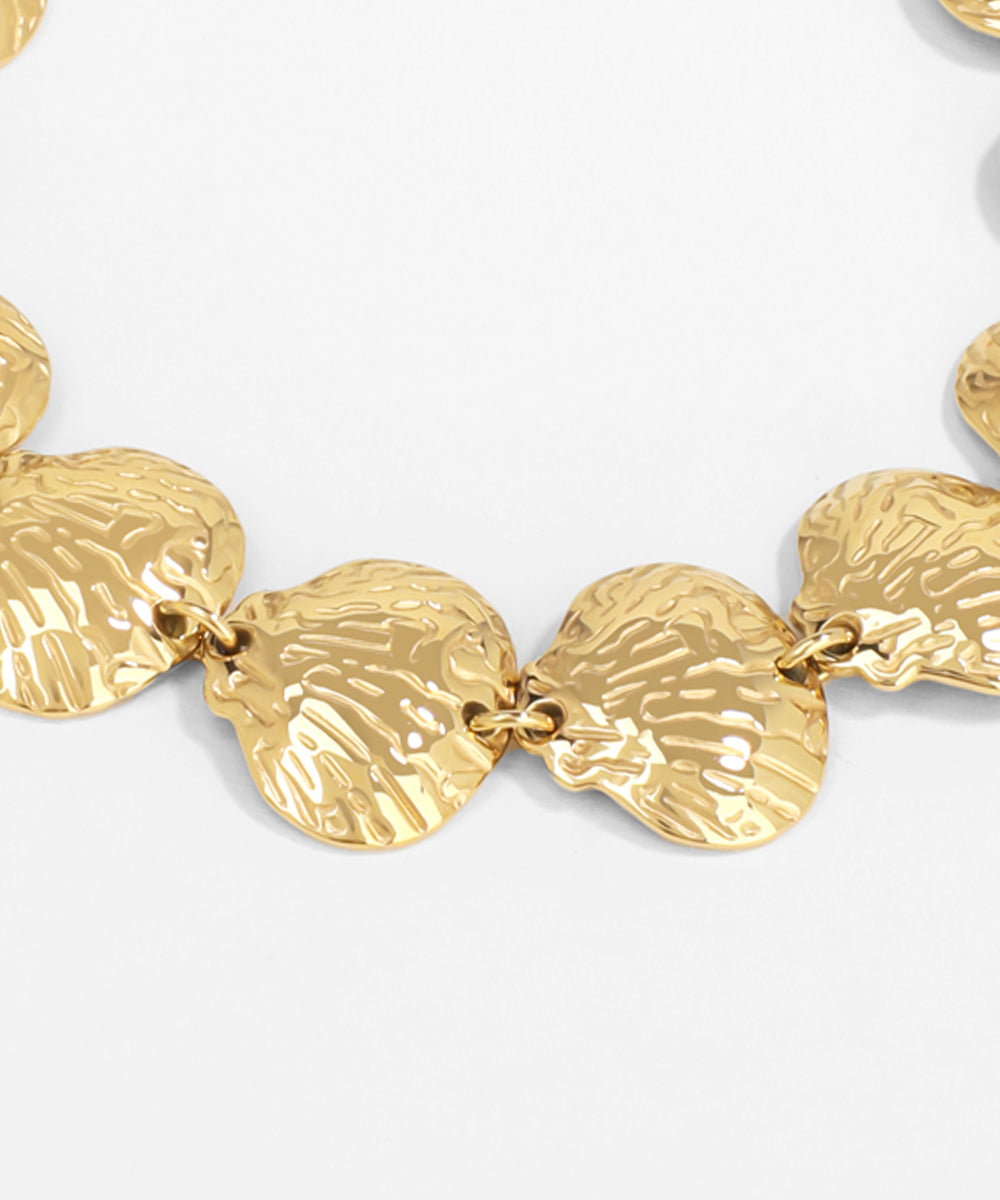 Gold bracelet with shell-like links on a light gray background