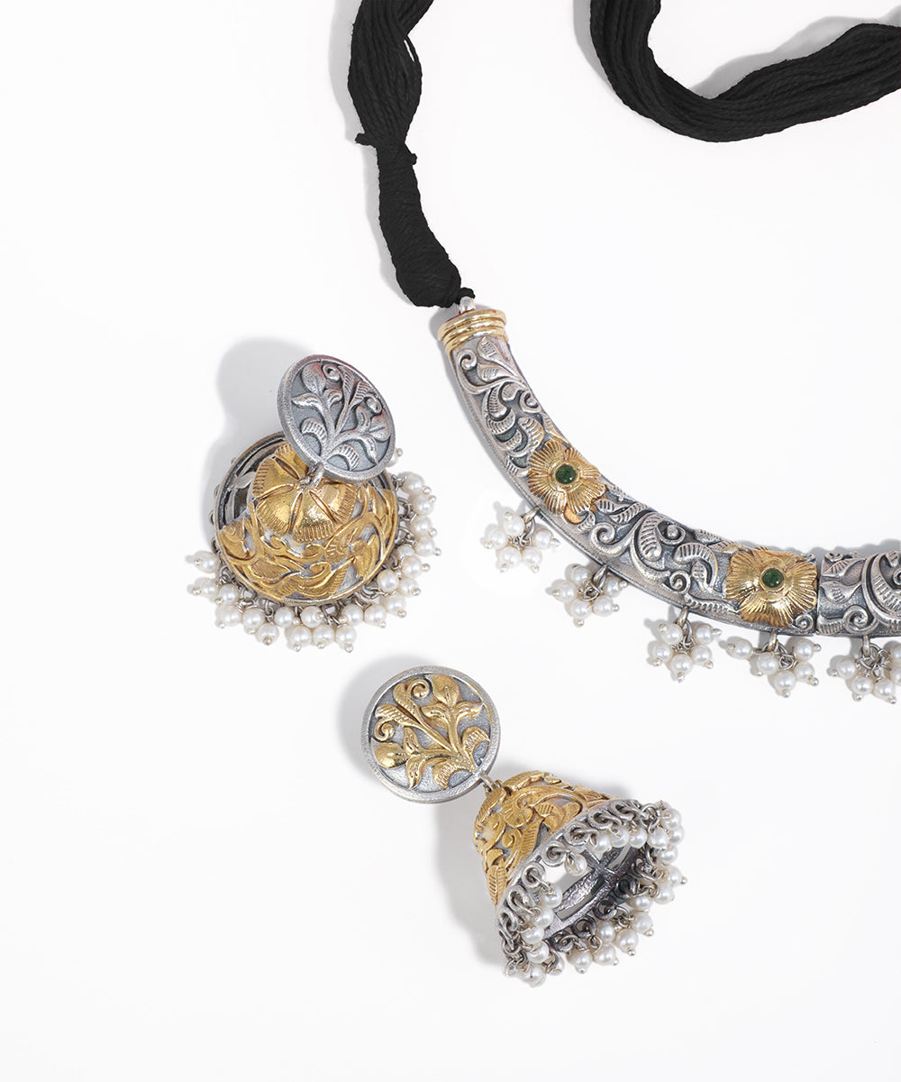 Decorative silver and gold necklace with black cord on a white background