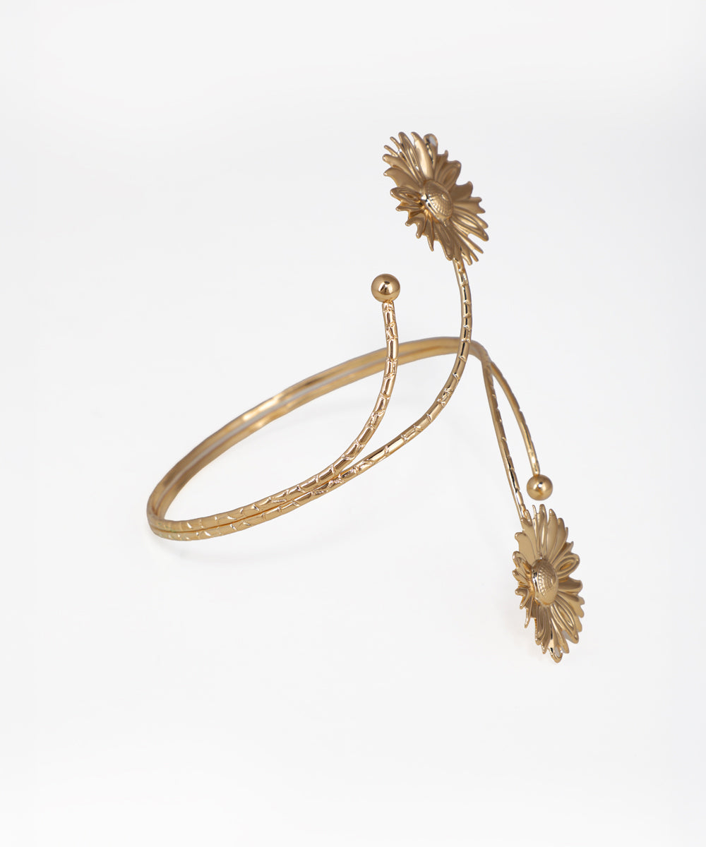 Gold bracelet with floral designs on a white background