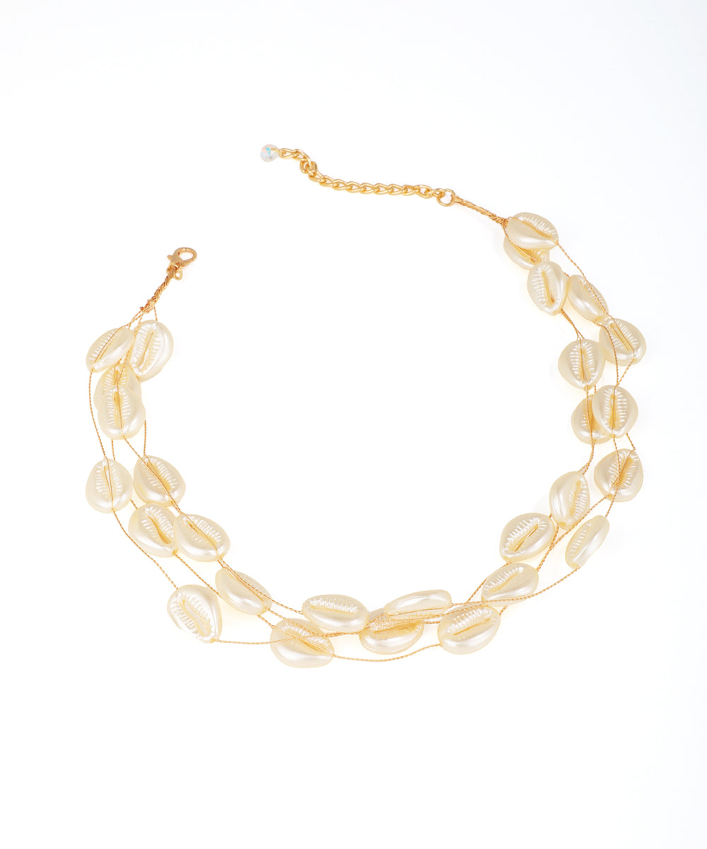 Gold-tone triple strand necklace with glossy shell-shaped beads and a lobster clasp.