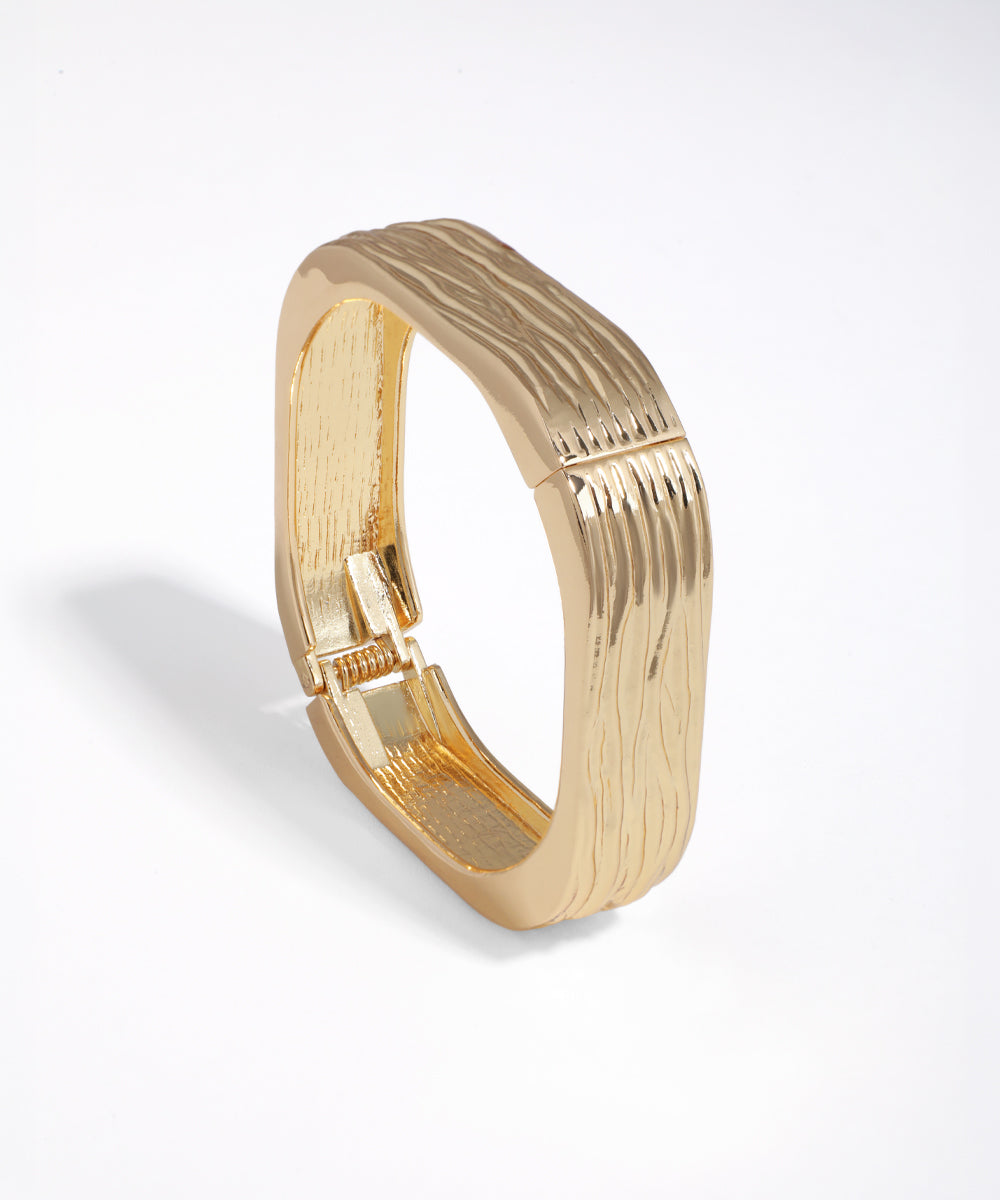 Gold-tone bangle bracelet with wavy textured surface and square profile
