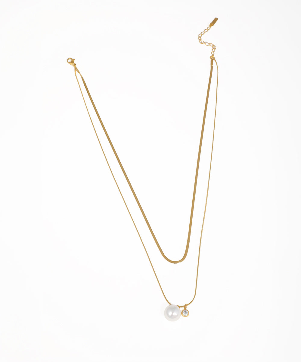Gold-tone layered necklace with snake chain and faux pearl and CZ charms