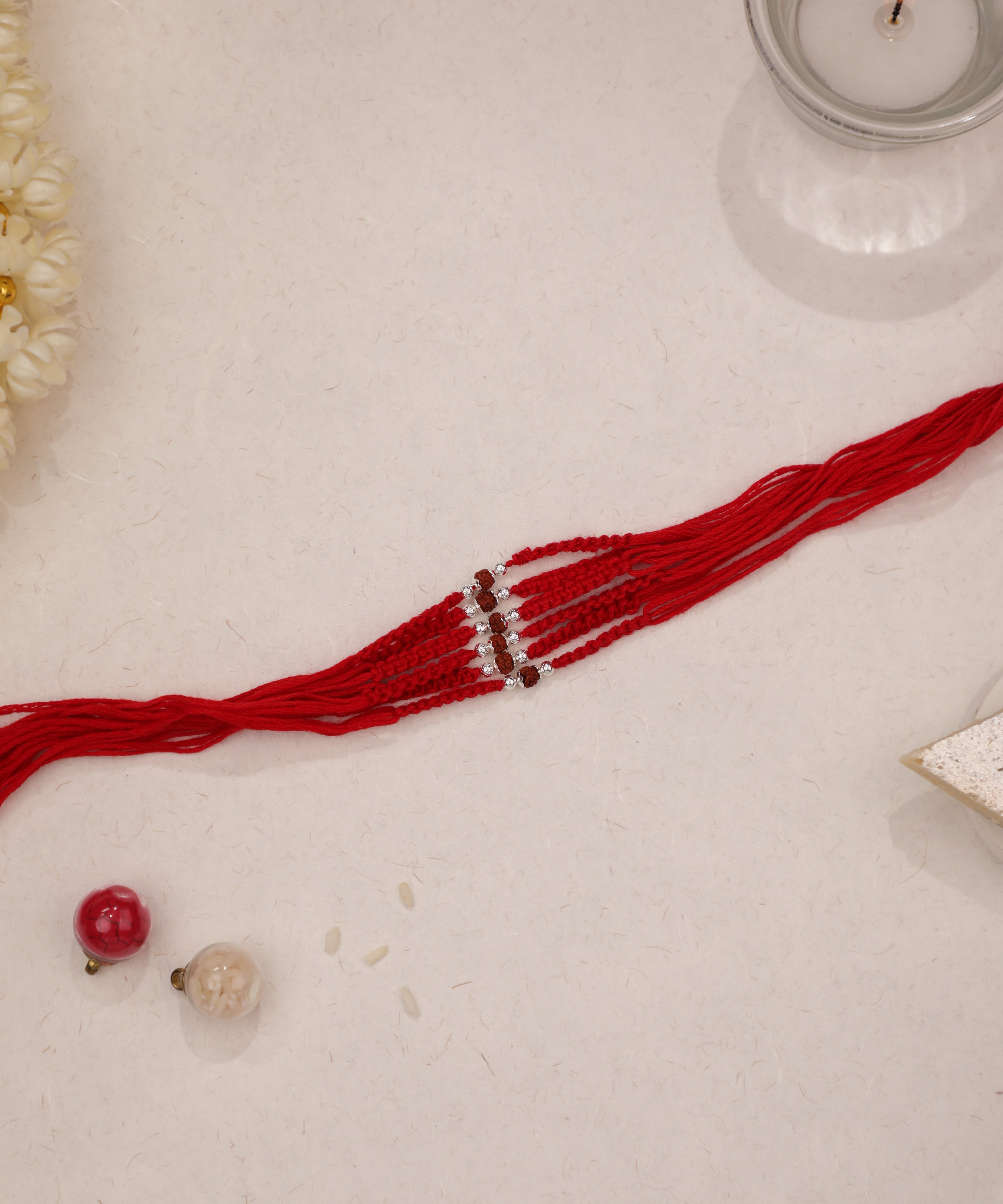 Red thread Rakhi with silver-tone bead details and clear sparkling stones