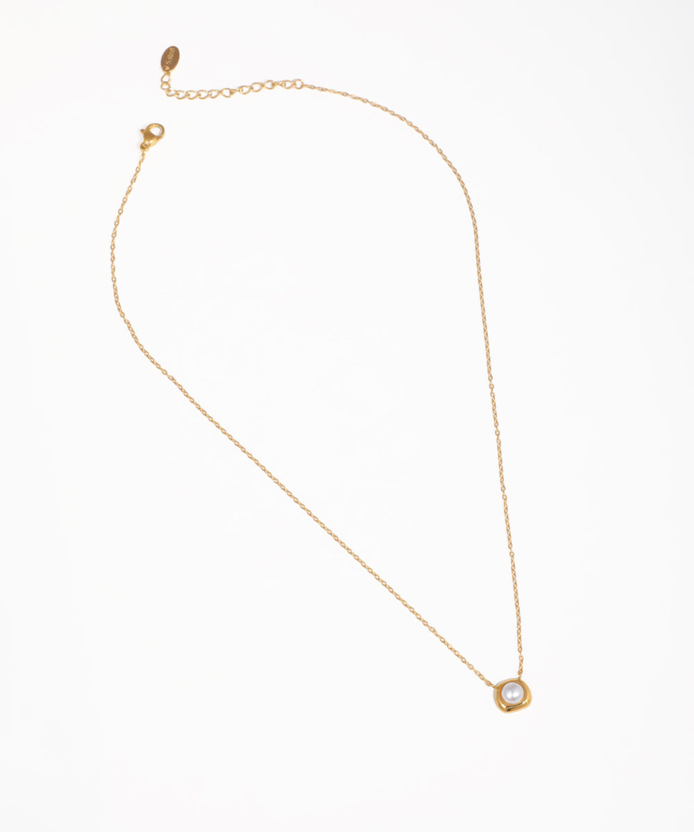 Gold-tone necklace with delicate chain and framed faux pearl orb pendant