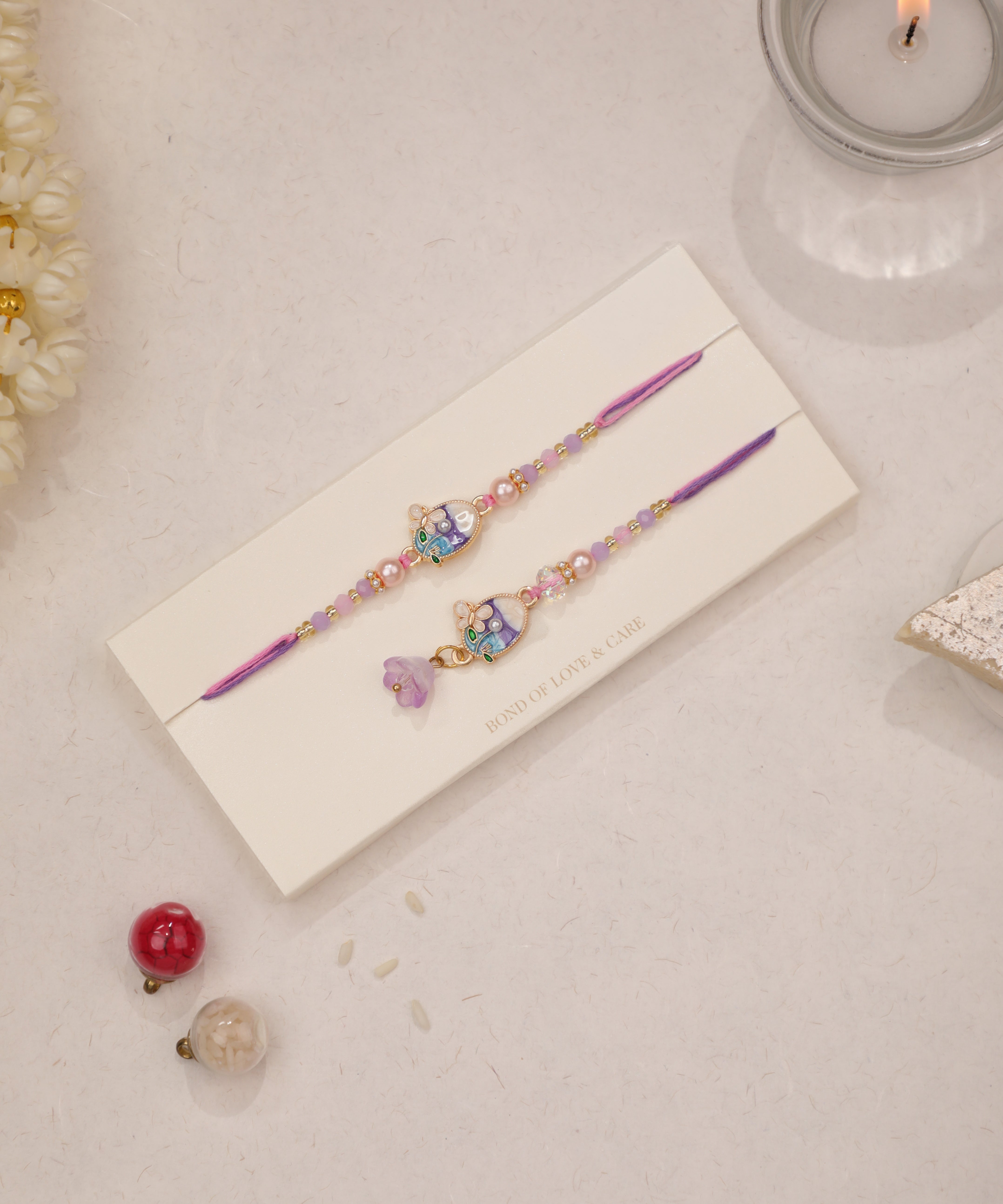 Gold-tone Rakhi set with enamel floral charms and purple & pink beads