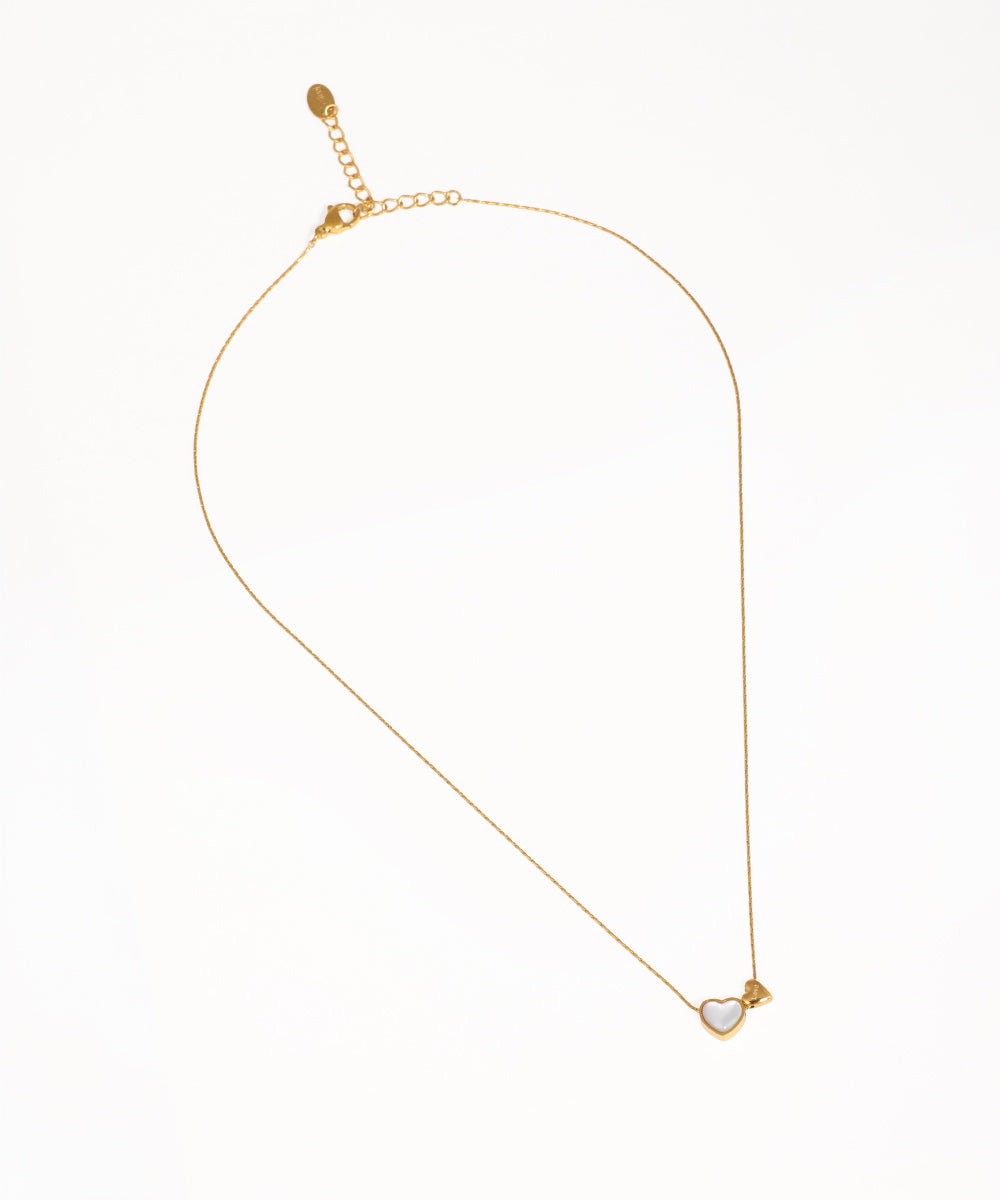 Gold-tone necklace with white heart inlay and small heart charm