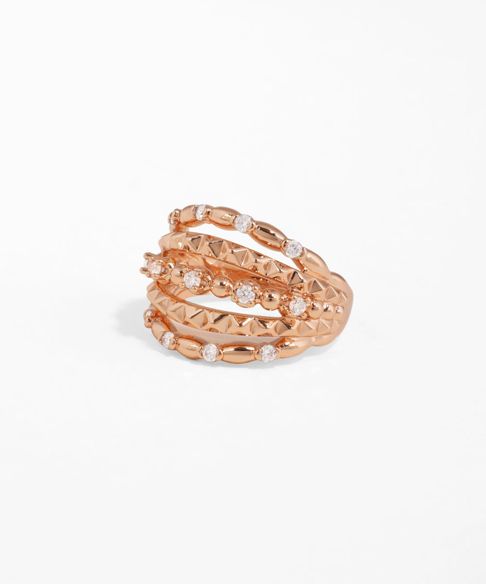 Rose gold spiral ring with embedded stones on a white background