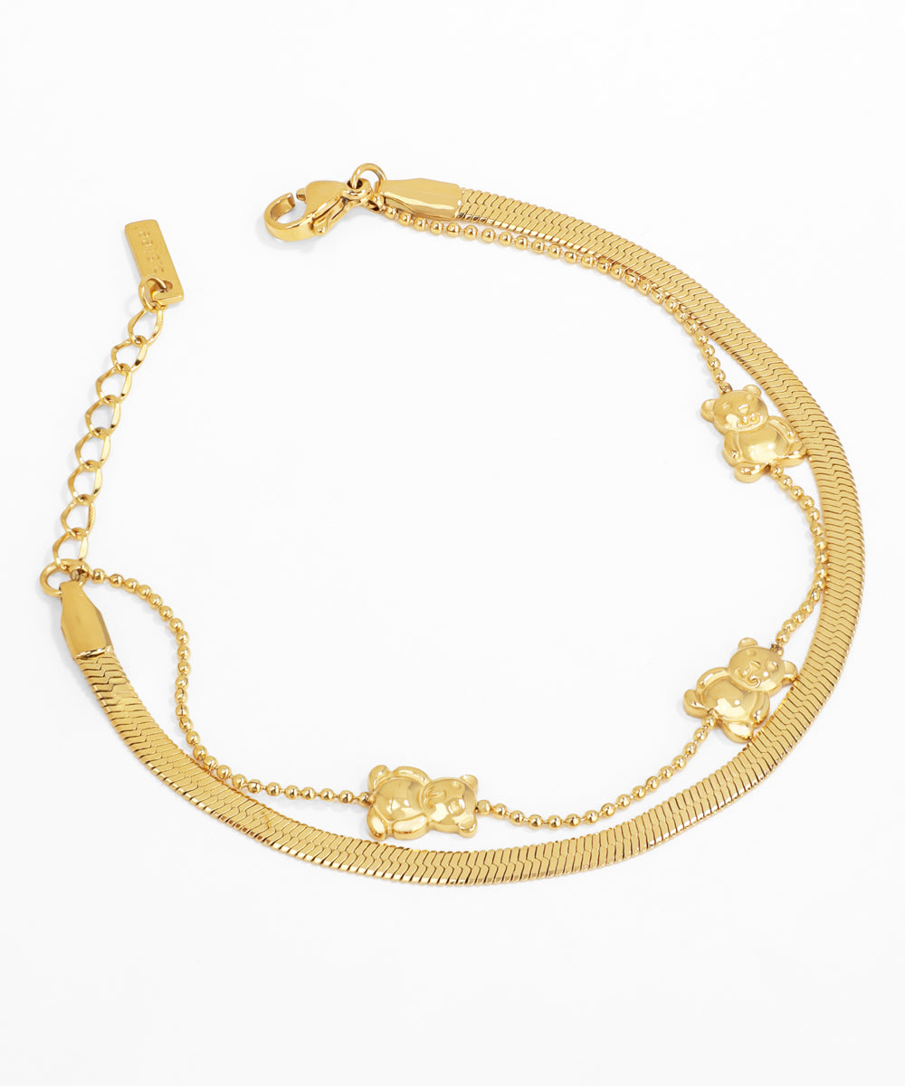 Gold bracelet with teddy bear charms on a white background