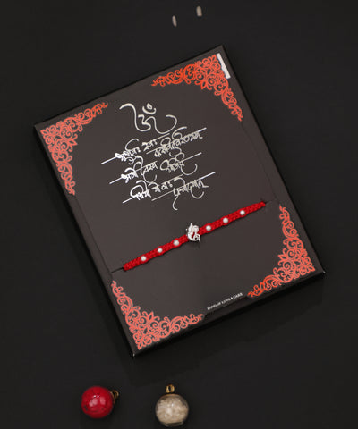 Rhodium finish Rakhi with Ganesha charm and white beads on a red thread