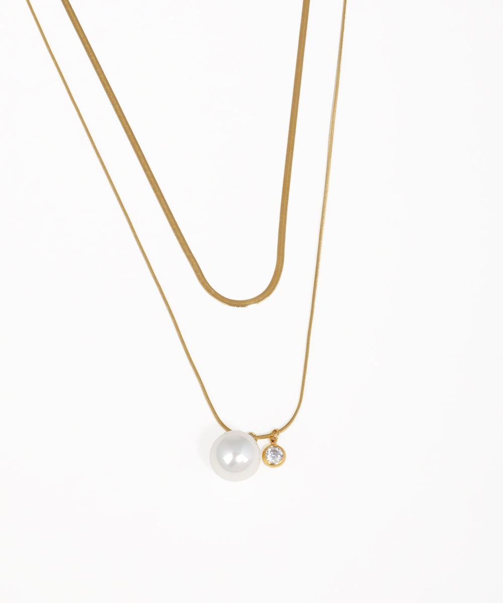 Layered gold snake chain necklace with pearl drop pendant and crystal charm