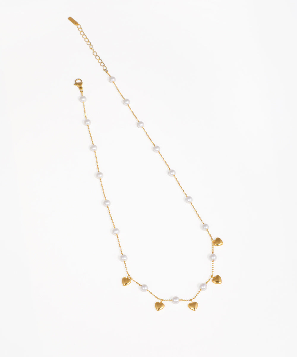 Gold-tone necklace with faux pearls and dangling heart charms.