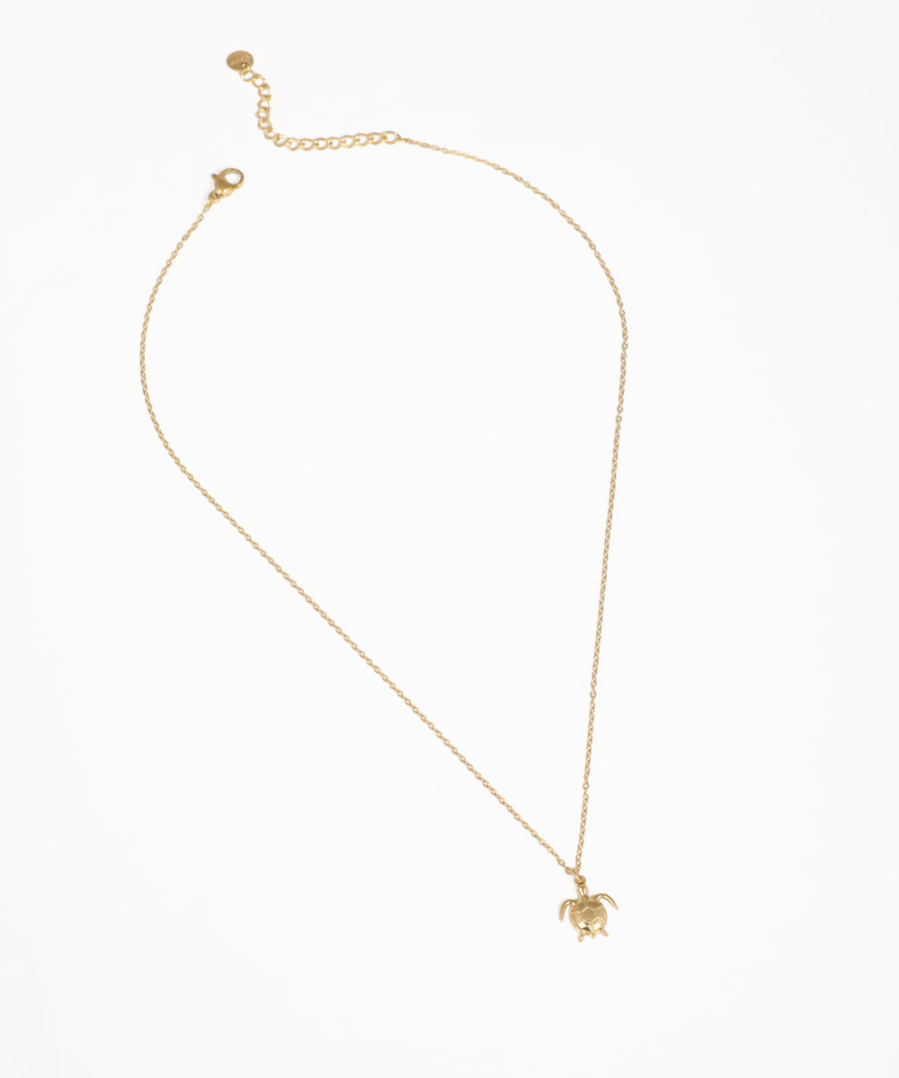 Gold-tone necklace with a small turtle pendant on a delicate chain.