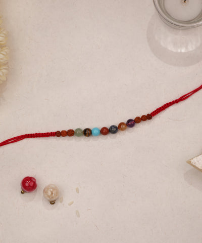 Red braided thread Rakhi with colorful beads and textured brown accents
