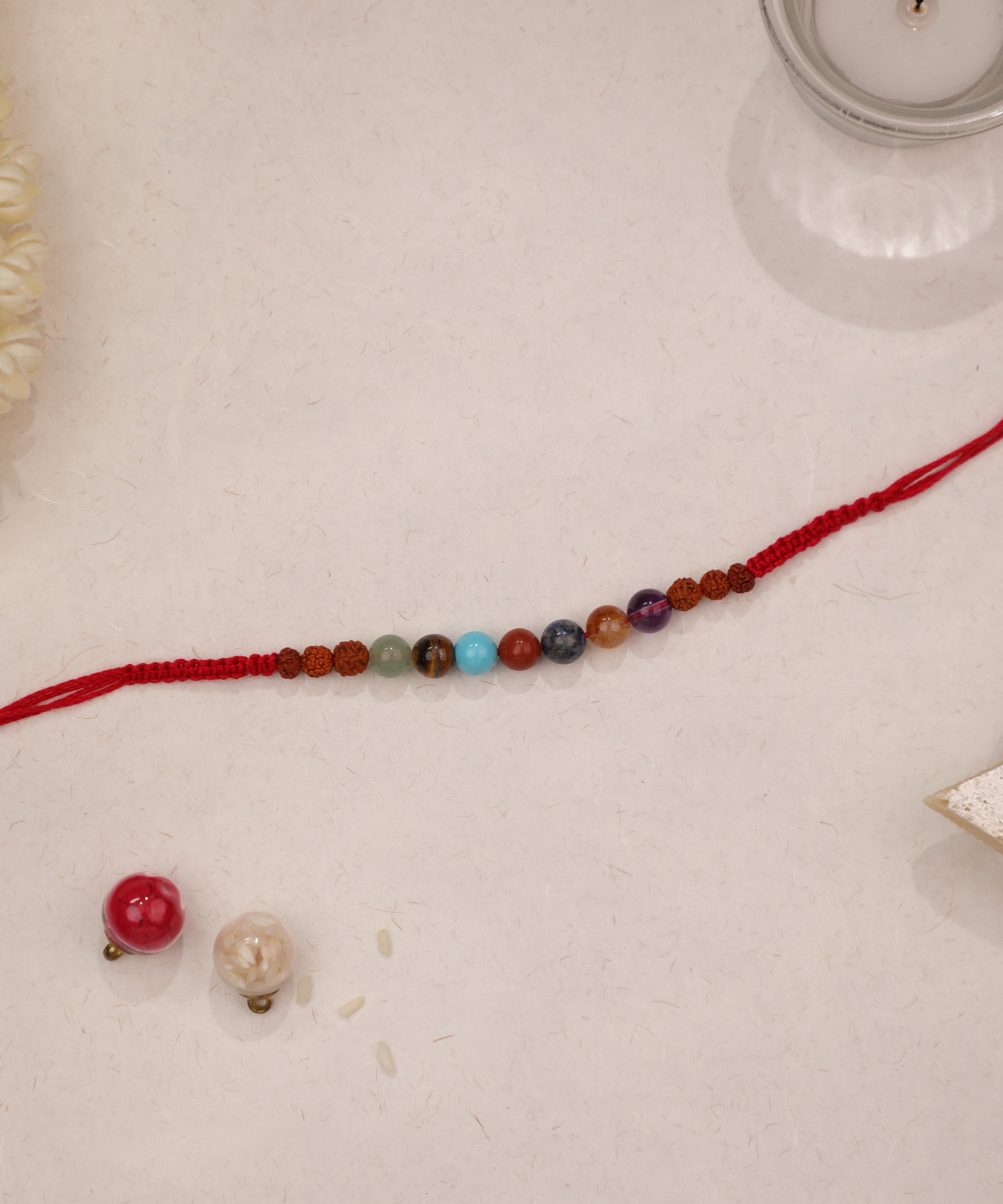Red braided thread Rakhi with colorful beads and textured brown accents