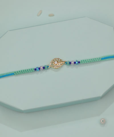 Gold-tone leaf motif Rakhi with clear CZ and blue-green beaded thread