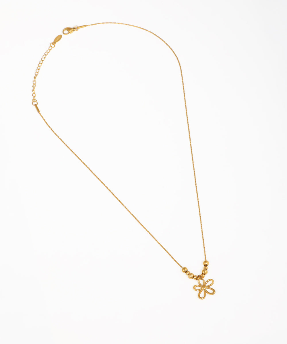 Gold-tone necklace with an openwork floral pendant and three small decorative beads on a delicate chain