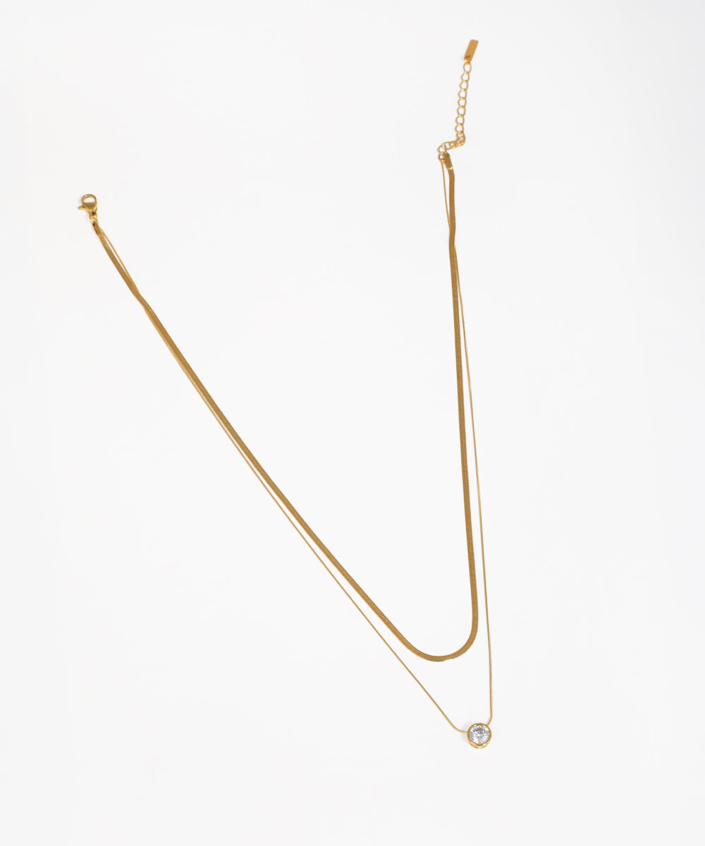 Gold-tone layered necklace with snake chain and round CZ solitaire pendant