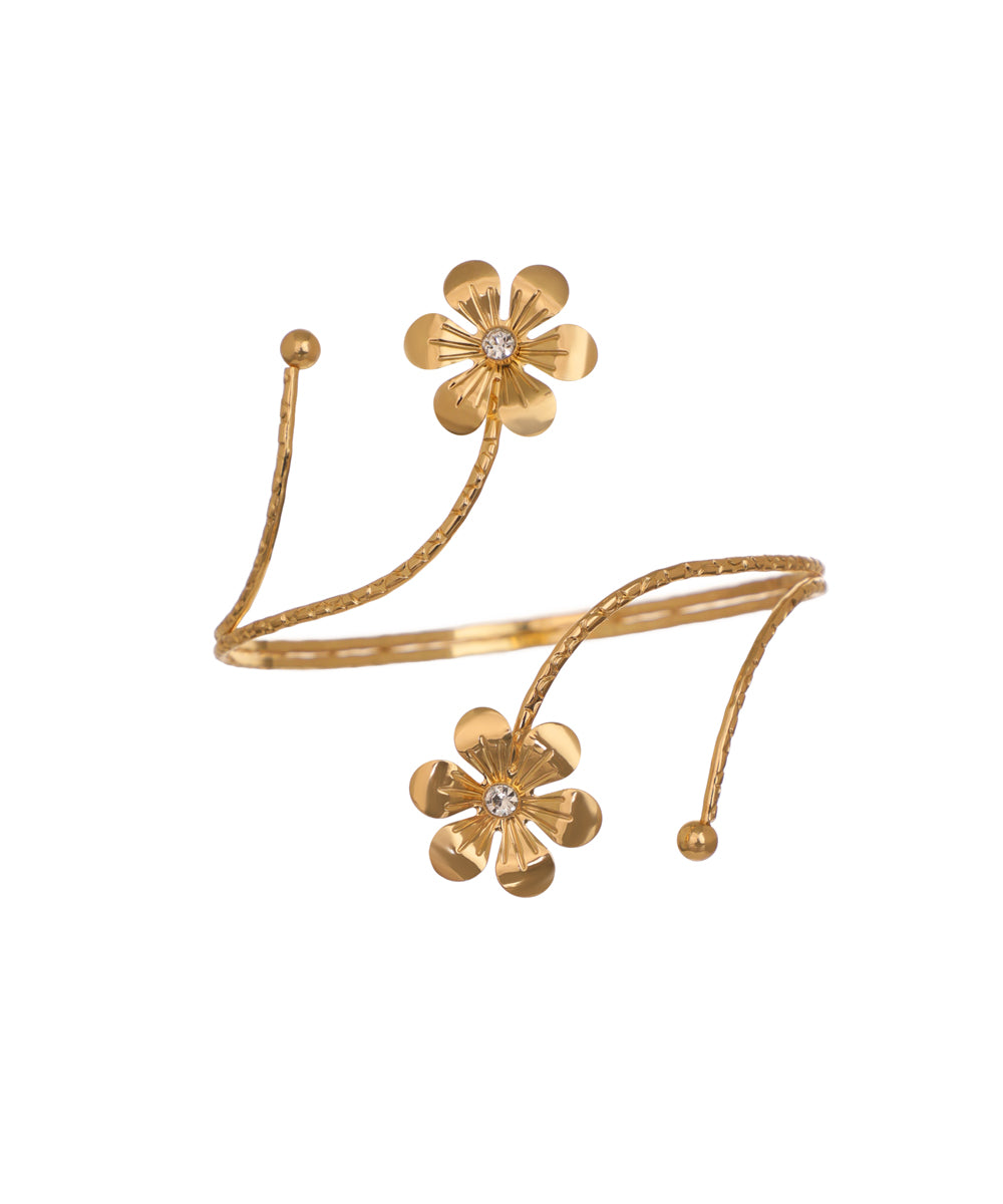 Gold-tone arm cuff with textured coil and two floral motifs with clear stones