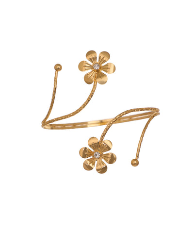 Gold-tone arm cuff with textured coil and two floral motifs with clear stones