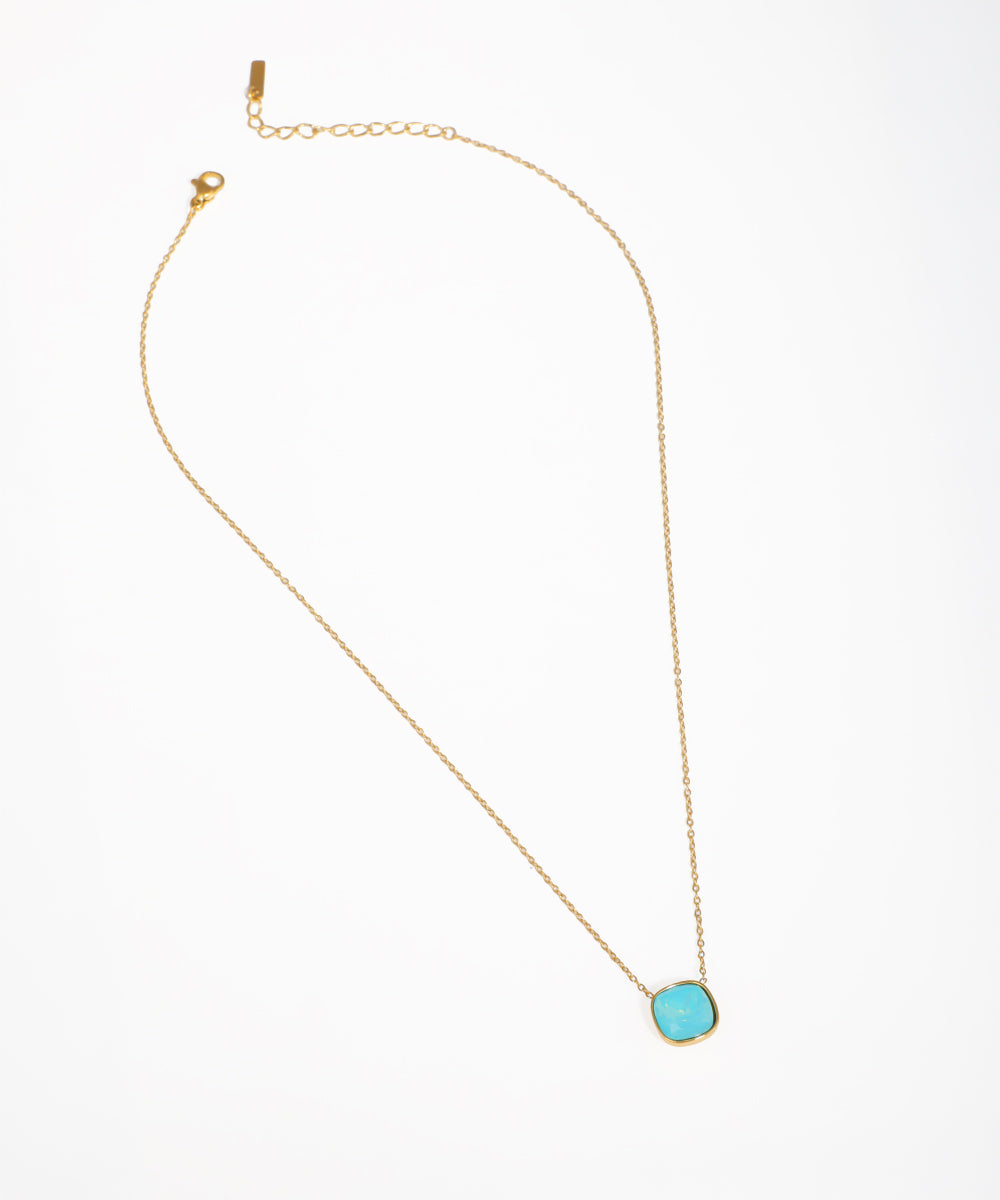 Gold-tone necklace with a square turquoise-tone glass crystal pendant and delicate chain.