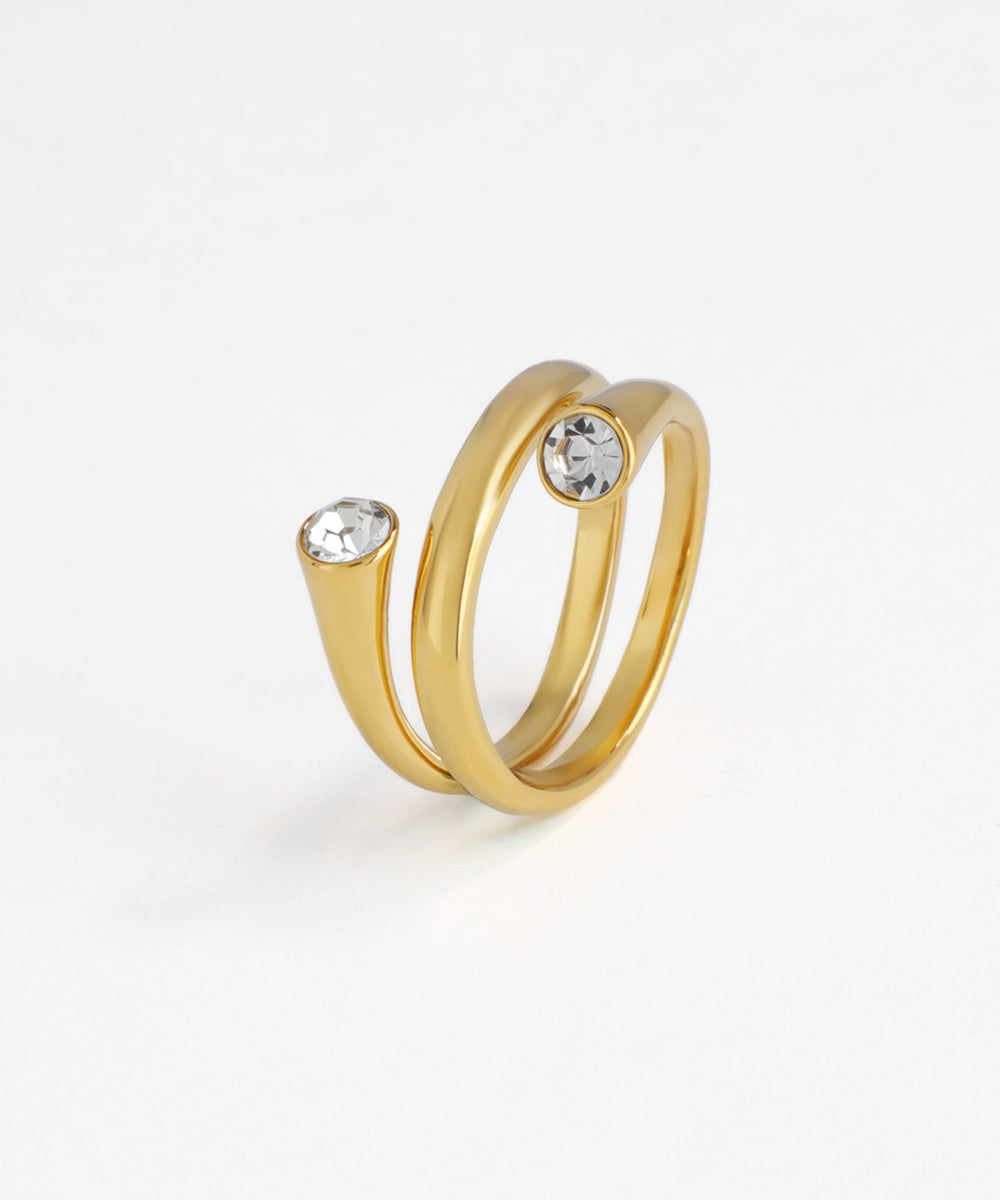 Gold-tone bypass ring with two round clear stones at open ends on white background