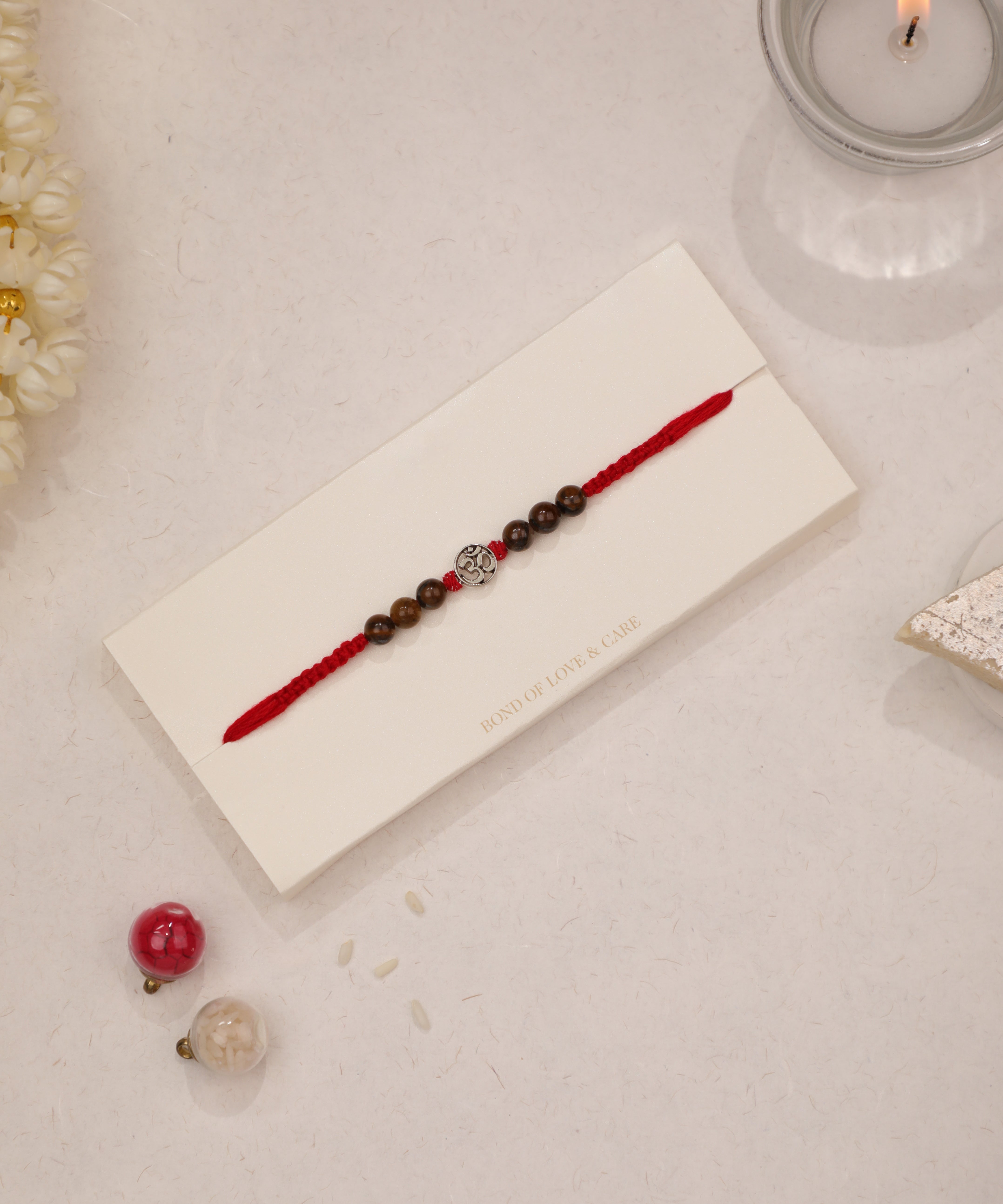 Red thread Rakhi with silver-tone Om charm and brown beads