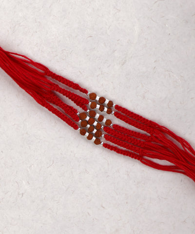 Red thread Rakhi with patterned brown seed beads and silver-tone accents
