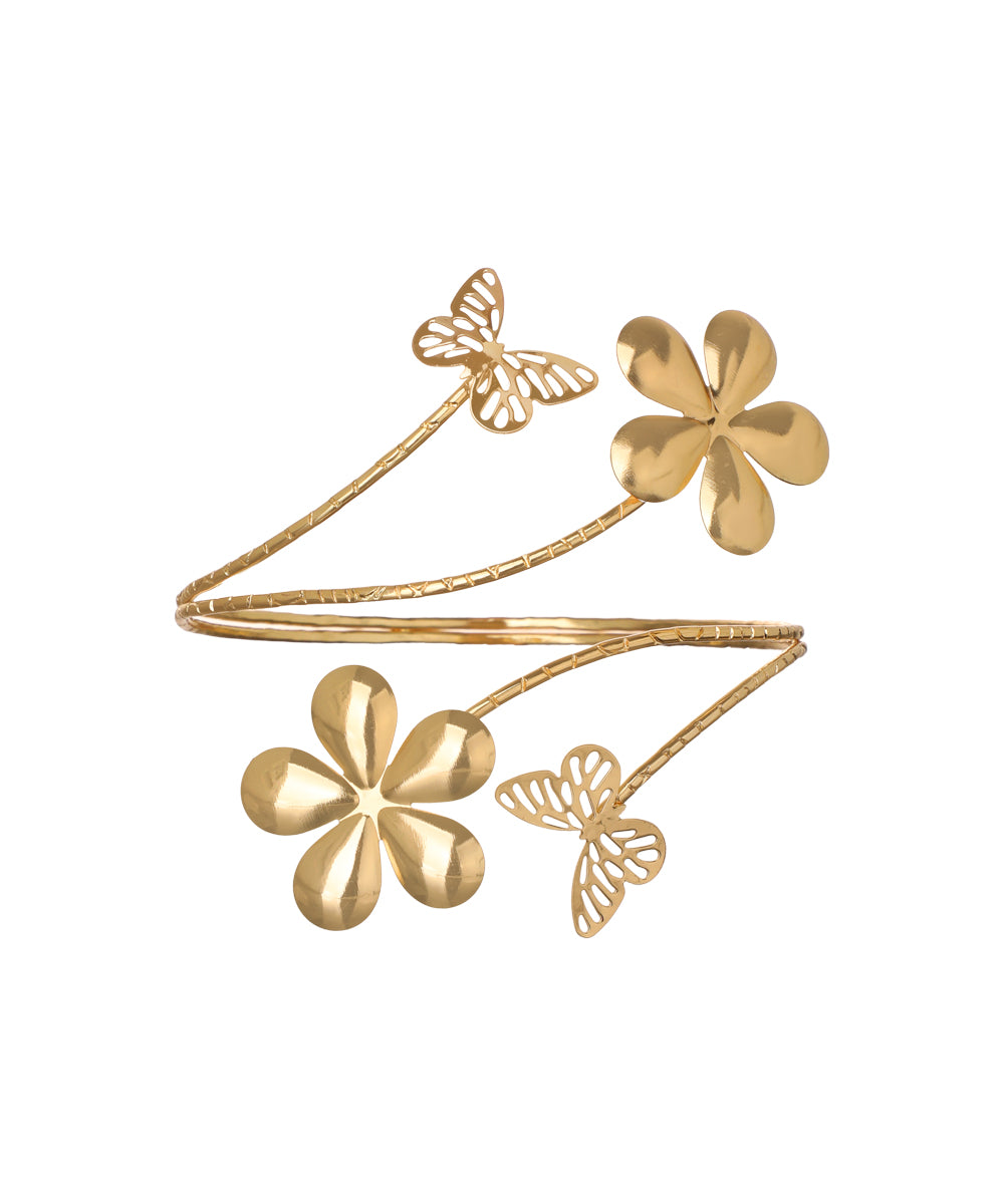 Gold-tone arm cuff with sculpted flowers and cut-out butterflies on a winding textured band