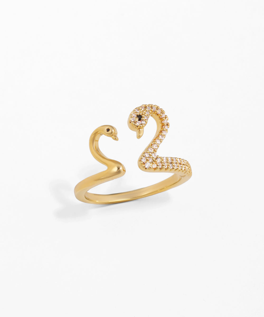 Gold swan-shaped ring with gemstones on a white background