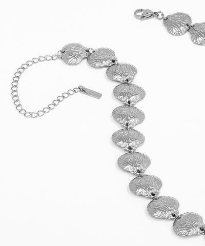 Silver bracelet with leaf-like patterns on a white background