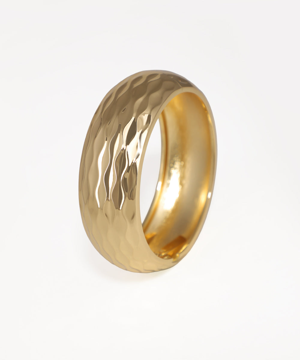Gold ring with a textured surface on a white background