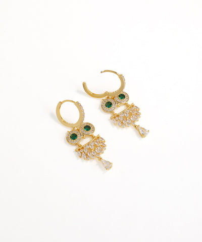 Gold earrings with green gemstones on a white background