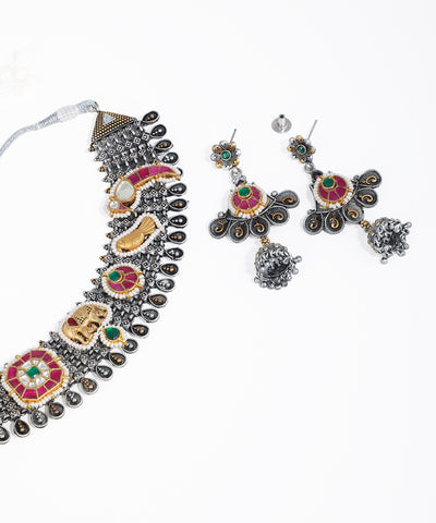 Ornate necklace and earrings set with colorful gemstones on a white background