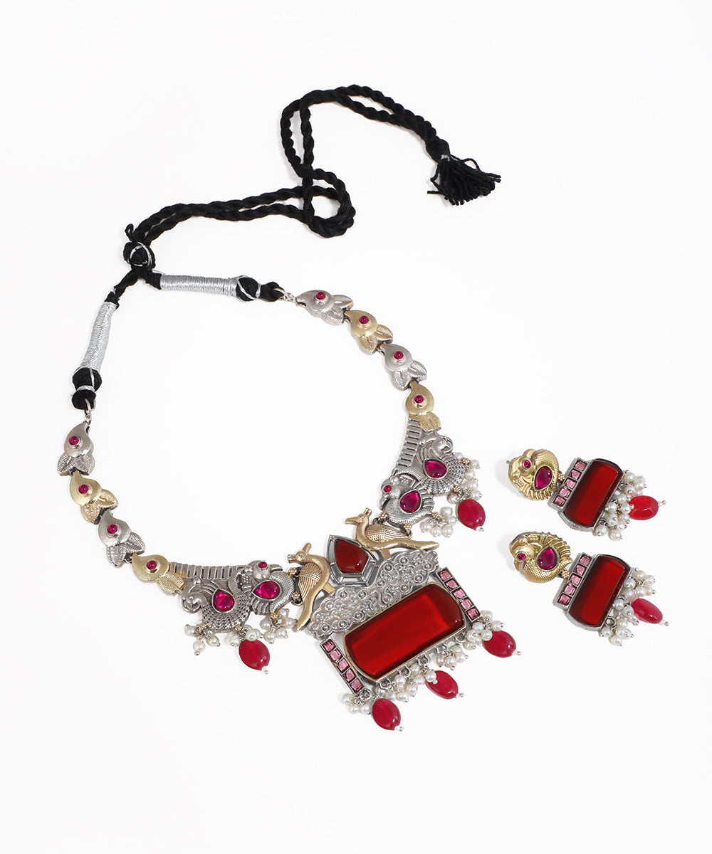 Jewelry set with necklace and earrings featuring red stones on a white background