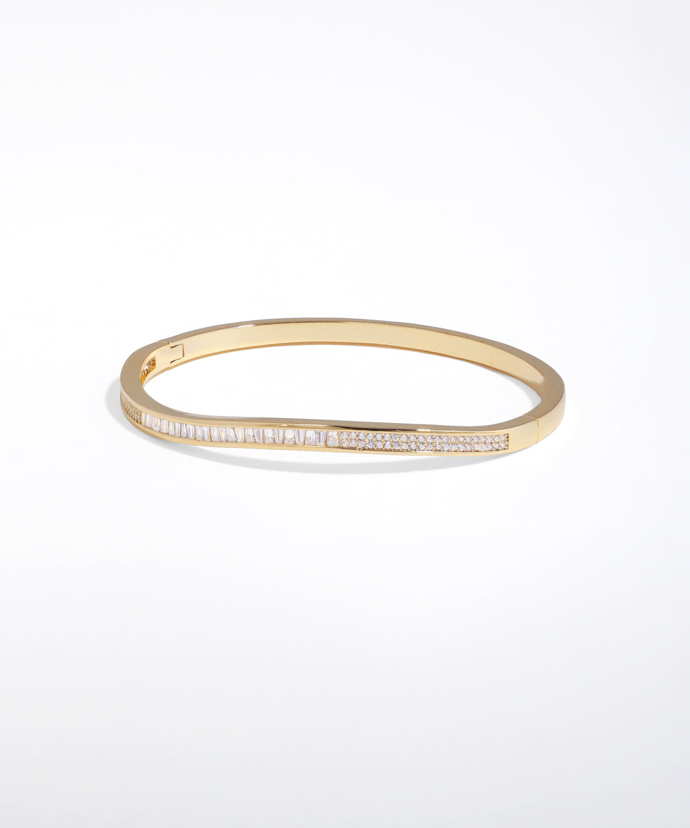 Gold bangle with embedded stones on a white background