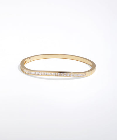 Gold bangle with embedded stones on a white background