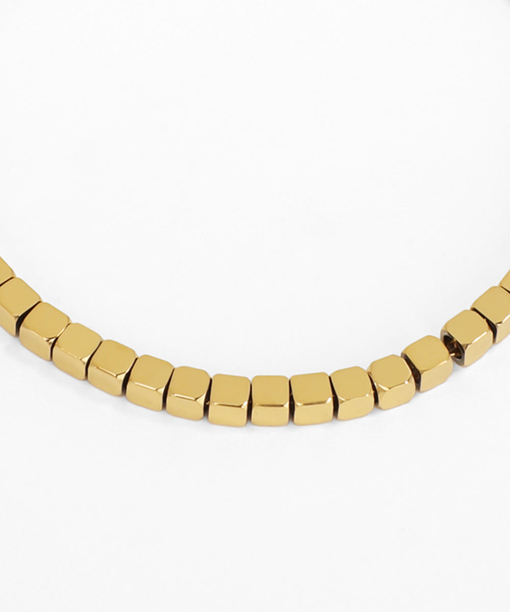 Gold beaded necklace on a white background