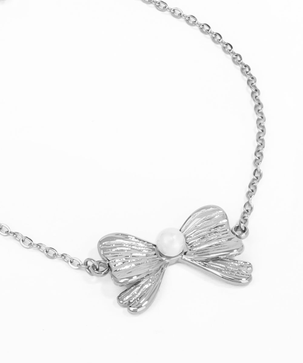 Silver bow-shaped pendant on a chain against a white background