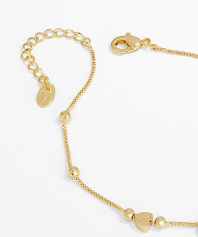 Gold bracelet with heart-shaped beads on a white background
