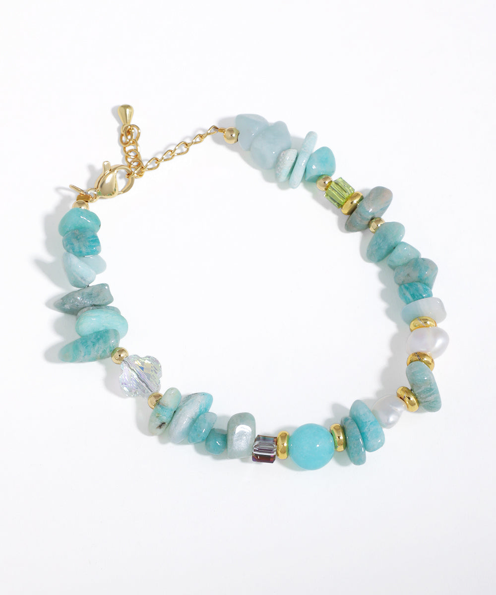 Gold-tone bracelet with irregular aqua beads, faux pearls, and assorted glass crystals on a white background.