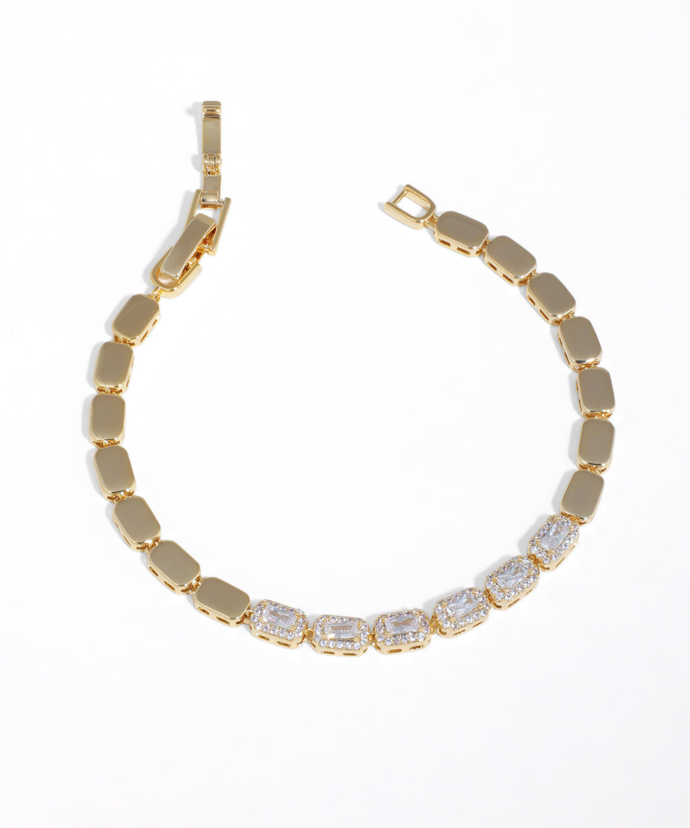 Gold-tone bracelet with alternating solid rectangular panels and emerald-cut CZ stones framed by smaller CZs.