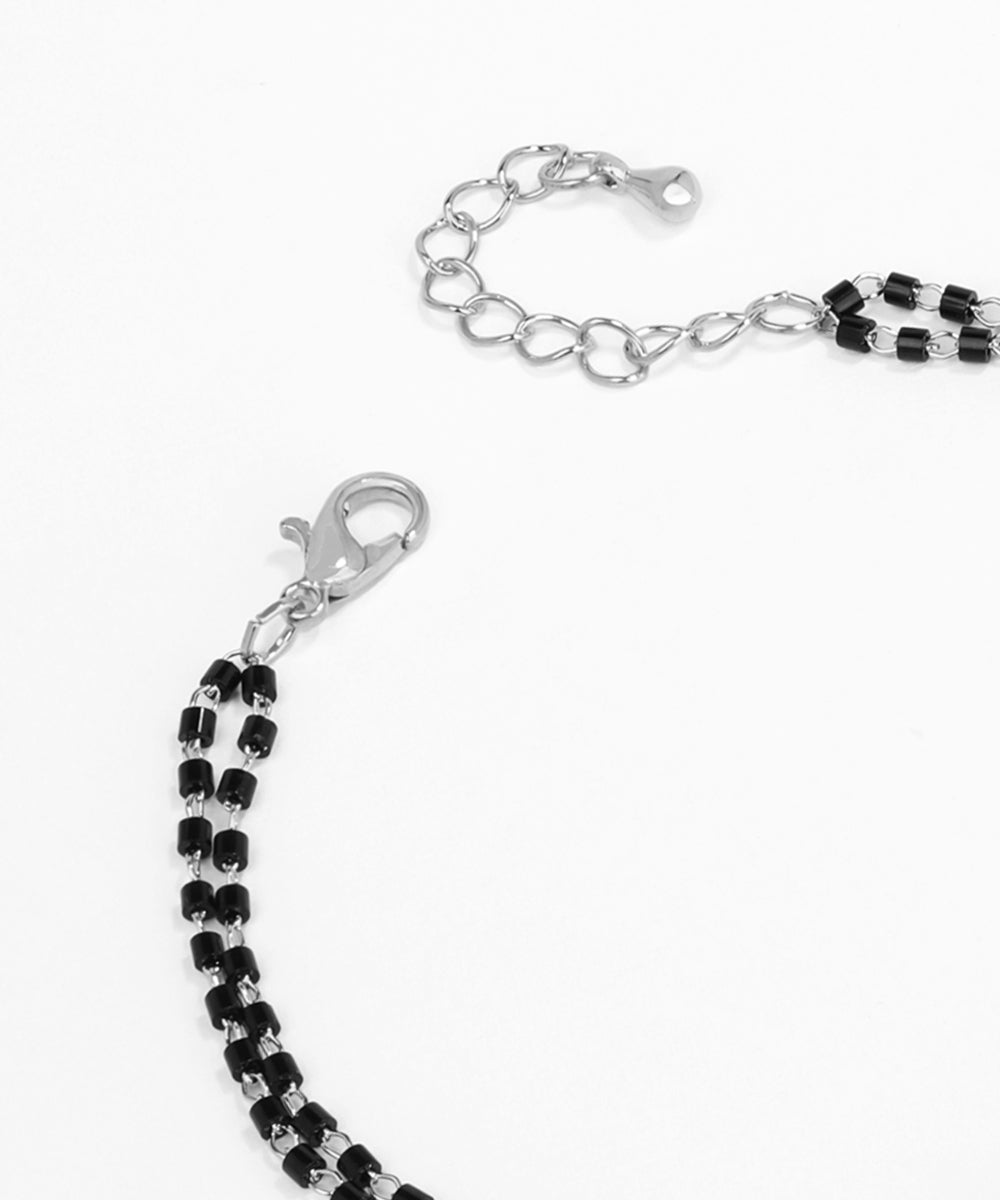 Silver chain with black beads on a white background
