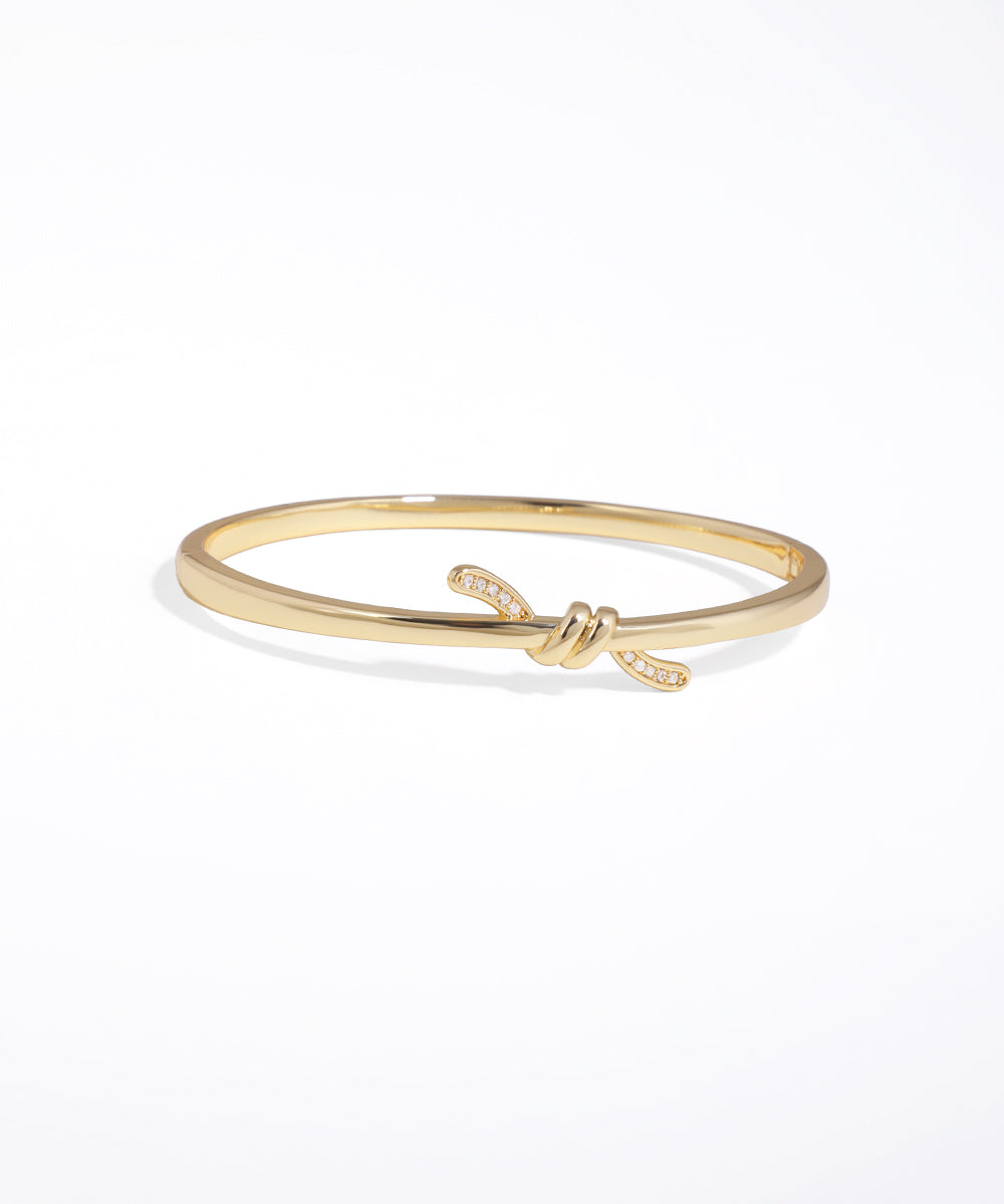 Gold bracelet with a knot design on a white background