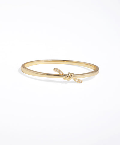 Gold bracelet with a knot design on a white background